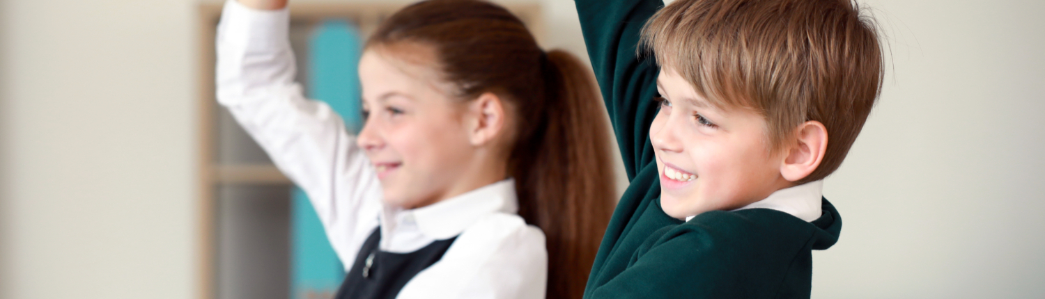 Cute little children raising hands during lesson in classroom